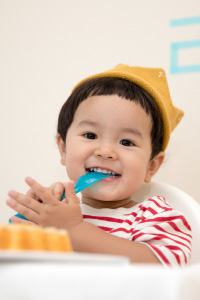 Male toddler wearing a crown and eating a piece of cake