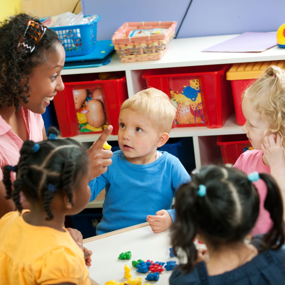 a group of children working with colorful items while a teacher helps