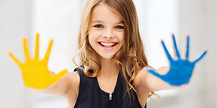 Young girl with blue and yellow paint on her outstretched hands